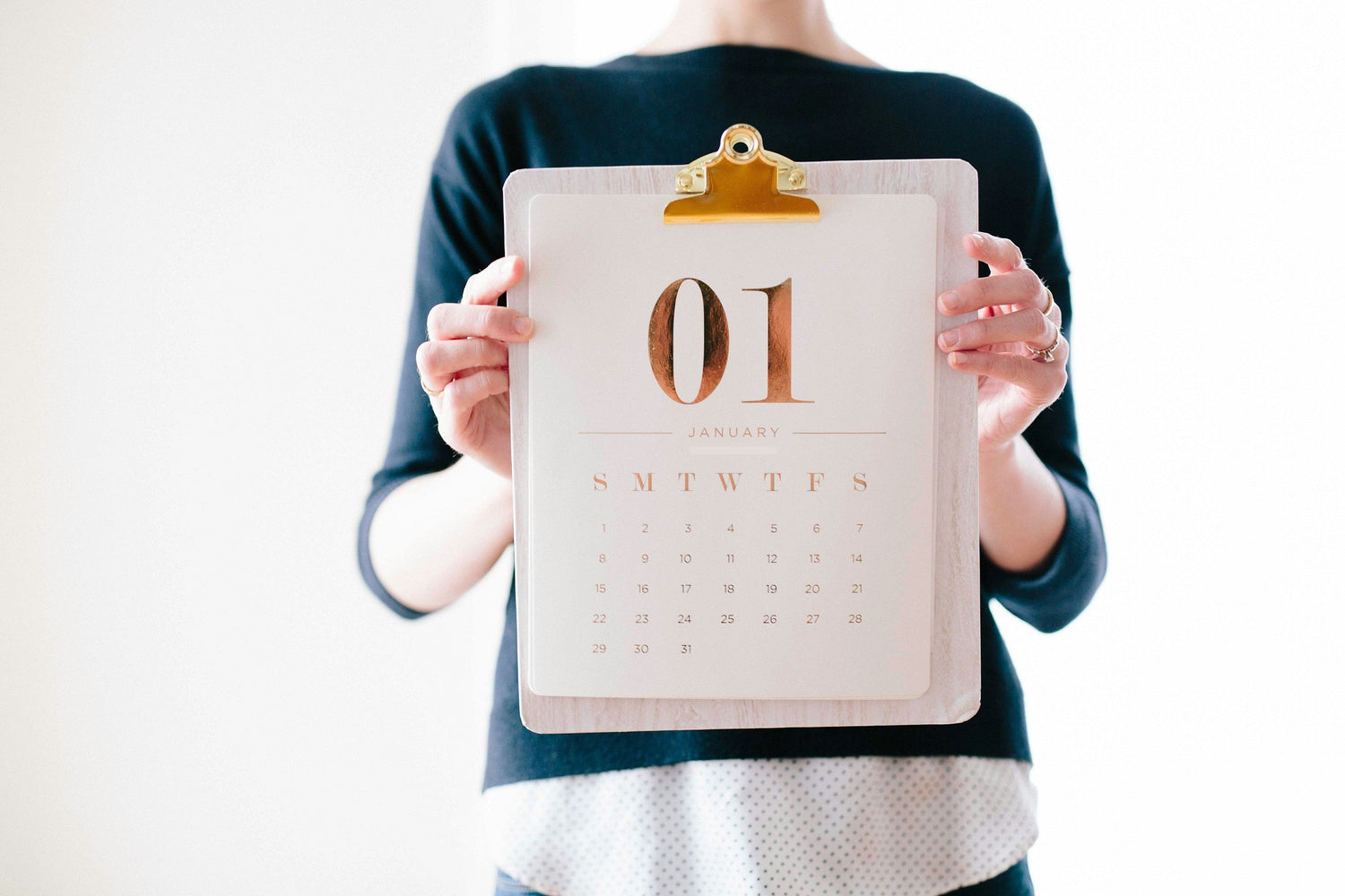 Woman holding clipboard with January calendar on it.