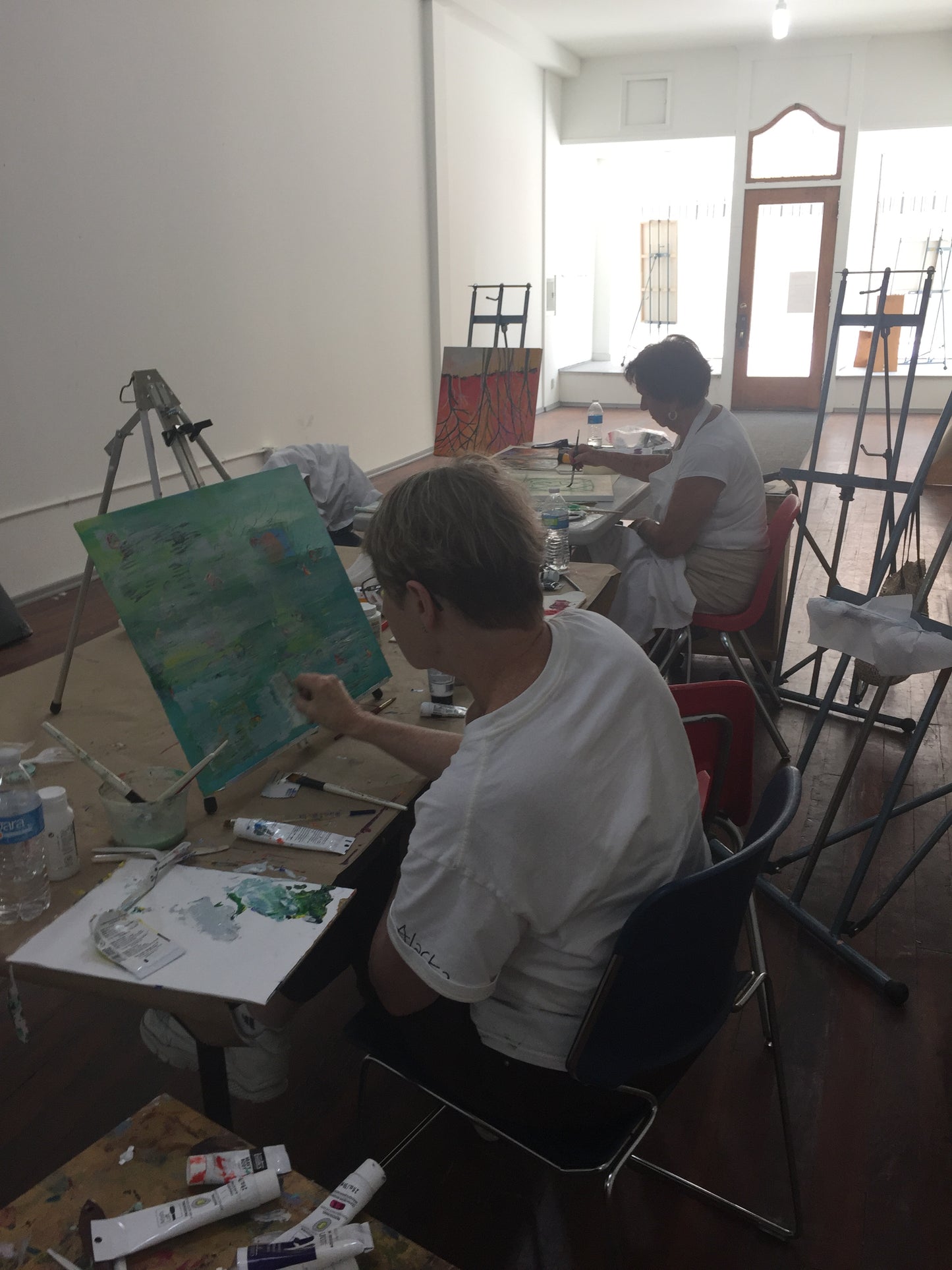 Art class in progress with students painting on easels in a classroom setting with art instructior Tonya Henderson.