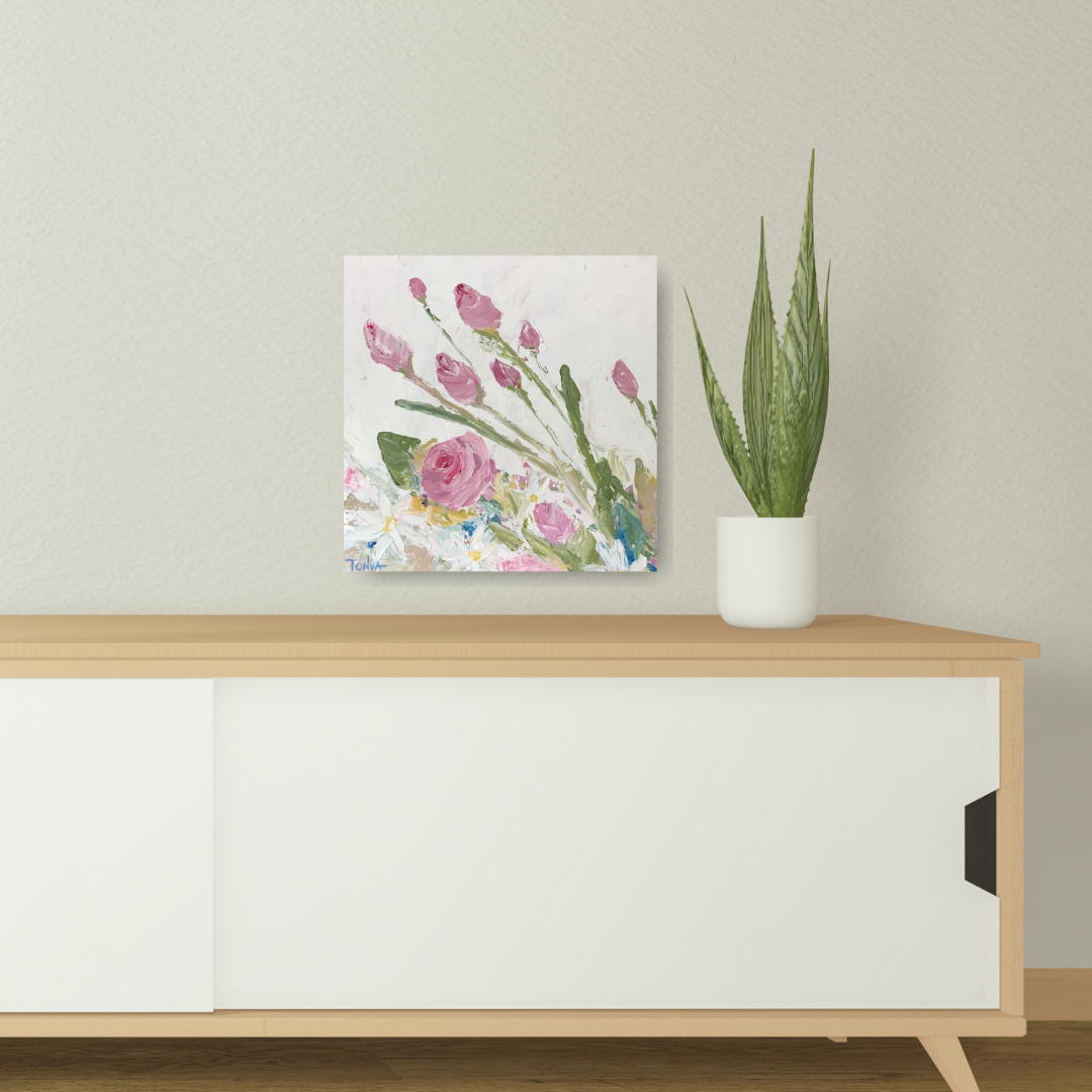 Floral knife painting with roses and daisies by artist Tonya Henderson on a wall above a wooden cabinet with a potted plant.
