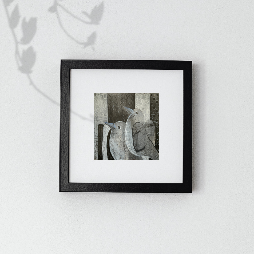 Framed artwork of two birds on a branch against a white background