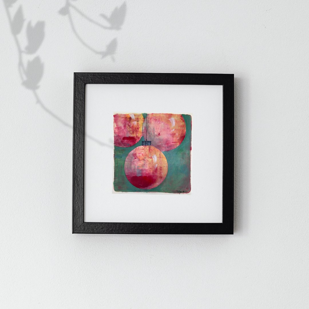 Framed artwork of holiday ornaments on a white wall, an original painting by artist Tonya Henderson.