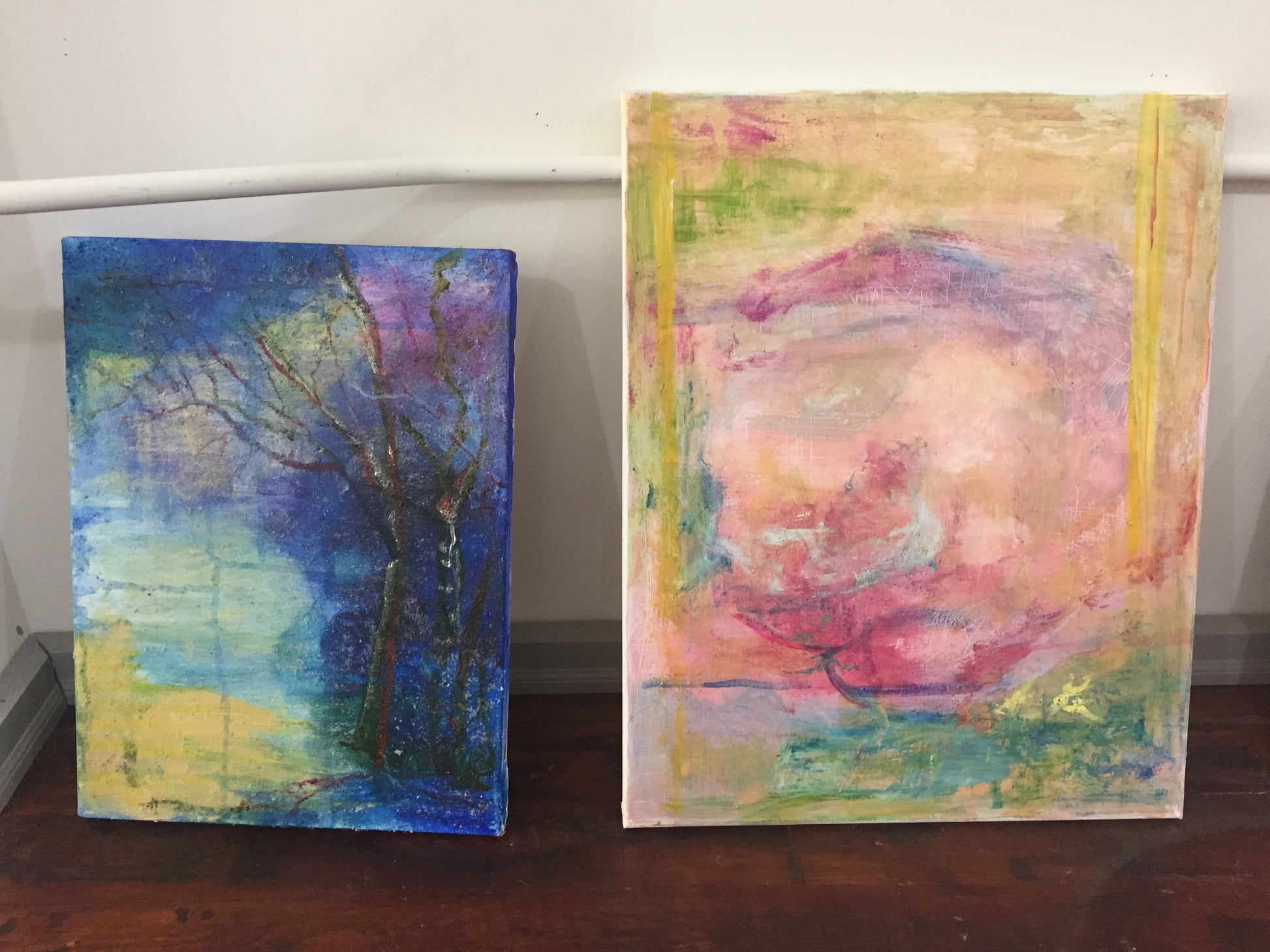 Two abstract art pieces on canvas surfaces with a white wall background at the end of class with art instructor Tonya Henderson.