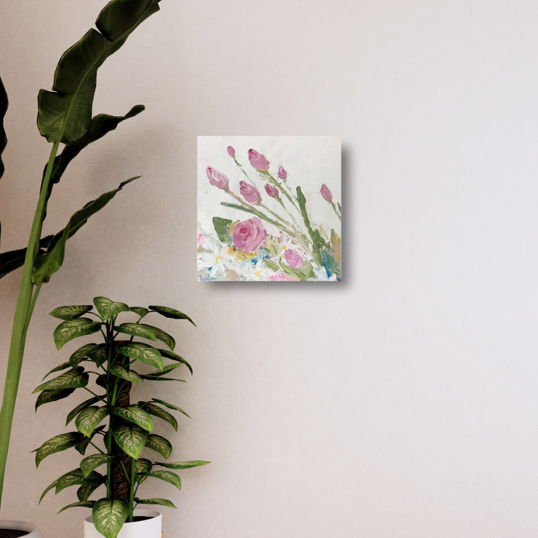 Rose and Daisy floral painting in pink, green, and white over a white background by artist Tonya Henderson. Hanging on a beige wall with plants to the side.