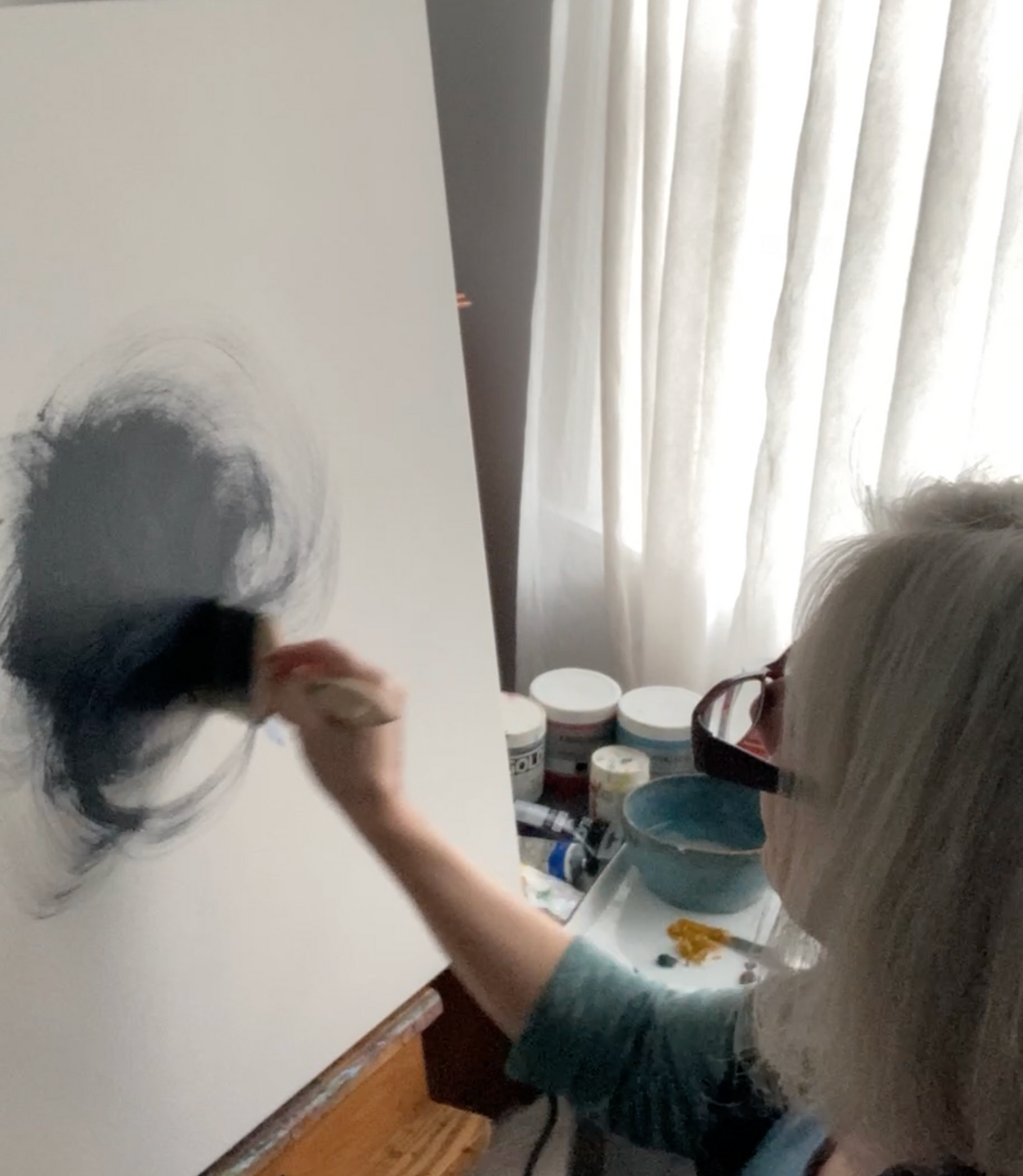 Artist Tonya Henderson painting on a large white canvas with a wide brush.